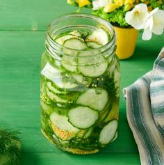 a jar filled with cucumbers sitting on top of a green table