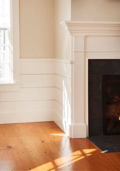 an empty living room with wood floors and a fire place in the fireplace mantel