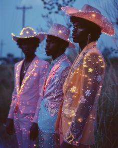 three black men wearing pink hats with stars all over them and lights on their bodies