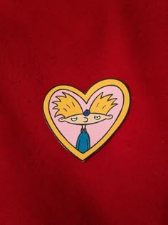 a red shirt with a pink heart shaped sticker on the chest and an image of a cartoon character