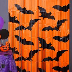 halloween decorations with bats and pumpkins in front of an orange curtain