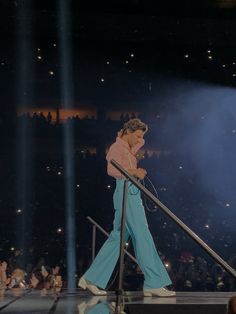 a woman in blue pants is walking down the stage with a microphone on her hand