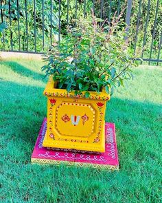 a yellow potted planter sitting on top of a red rug in the grass