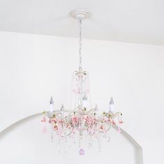 a chandelier hanging from the ceiling in a room with white walls and pink flowers