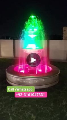 a water fountain with green and pink lights