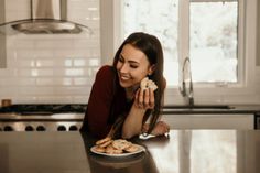 a woman laying on the kitchen counter eating cookies