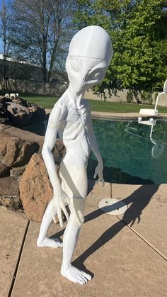 a white statue is standing in front of a pool