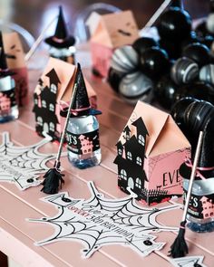 halloween decorations are displayed on a table with black and white paper houses in the background