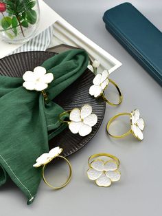 three pieces of jewelry sitting on top of a black plate next to a green napkin