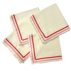 three white napkins with red and pink trim