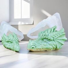 two plastic dragon heads sitting on top of a white counter next to a window sill