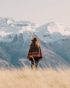 a person standing in tall grass with mountains in the background and an arabic quote on it