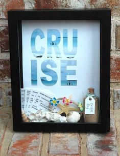 there is a framed sign with some shells and other items in it on the brick wall