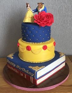 a three tiered cake decorated with beauty and the beast figurines on top of books