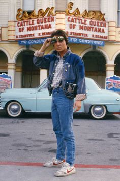 a man standing in front of a movie theater with his hand on his head while wearing sunglasses