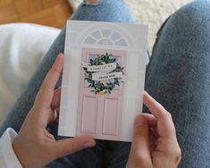 a person holding up a card with a wreath on the front and side of it