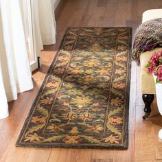 a large rug on the floor next to a chair and vase with flowers in it