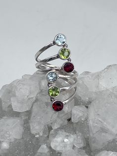 Multi-Gemstone Ring, Size -Various Adjustable Garnet, Peridot, and Blue Topaz 925 Sterling Silver WWW.KARINSFORGOTTENTREASURES.COM Multi-stone Round Jewelry For May Birthstone, Round Multi-stone Gemstones For May Birthstone, Green Sterling Silver Topaz Ring, Sterling Silver Topaz Gemstone Ring, Peridot Jewelry With Gemstone Accents, Sterling Silver Multi-stone Ruby Ring, Sterling Silver Multi-stone Round Ruby Ring, Stackable Peridot Jewelry For Anniversary, Silver Ring With Peridot Birthstone