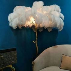 a lamp that is on top of a table with feathers hanging from it's base