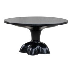 a black table with an oval glass top and metal base, on a white background