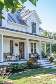 a white house with lots of windows and plants on the front porch