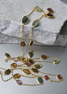 Perfect slices of genuine natural Tourmaline, in a myriad of shades. all stones are slices and have been rose-cut. included is Green, Pink Tourmaline, Brown, Golden etc...just stunning. The striking 14k gold vermeil provides the perfect contrast to the Tourmaline gem. No cheap metals - just 925 Sterling Silver with 14k gold plate. What may look like cracks in the gemstone, are actually natural inclusions. Length is 36 inches. Lobster clasp. Yellow Gold Tourmaline Necklace With Natural Stones, Oval Tourmaline Natural Gemstones, Oval Tourmaline Gemstones, Gold Tourmaline Multi-stone Necklace, Gold Multi-stone Tourmaline Necklaces, Multicolor Tourmaline Jewelry With Stones, Paste Jewelry, Flapper Necklace, Pink Tourmaline