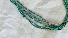 "5 gorgeous strands of hand hewn tiny natural turquoise beads and three strands of miniscule sterling silver beads from the Karen Hill Tribe of Thailand . Approx 17\" long" Turquoise Multi-strand Bracelets With Tiny Beads, Turquoise Multi-strand Jewelry With Tiny Beads, Bohemian Multi-strand Jewelry With Tiny Beads, Artisan Multi-strand Jewelry With Tiny Beads, Bohemian Double Strand Jewelry With Tiny Beads, Unique Turquoise Jewelry With Tiny Beads, Southwestern Multi-strand Turquoise Jewelry, Silver Heishi Beads Hand-strung Jewelry, Silver Heishi Beads Jewelry Hand-strung