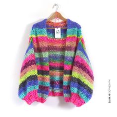 a multicolored sweater hanging on a hanger against a white wall with a price tag