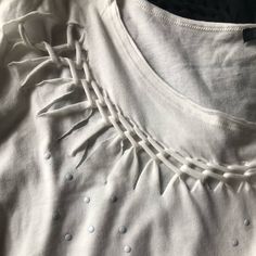 a close up of a white shirt with holes on the front and back of it