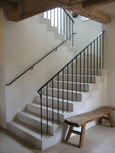 a wooden bench sitting under a stair case next to a set of white staircases