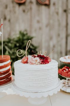 a white cake sitting on top of a table next to other desserts and cakes