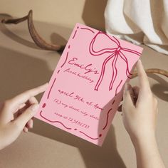 a person holding up a pink card with a bow on it