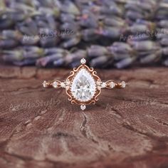 a close up of a ring on a table with lavender flowers in the back ground