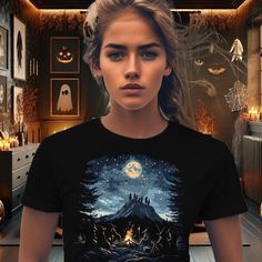 Embrace the mystical allure of the wilderness with our "Witches' Mountain Gathering" T-Shirt. This unique design captures a group of witches gathered at the top of a mountain, around a crackling campfire, under a starry night sky illuminated by a full moon. The scene masterfully blends elements of the great outdoors--like hiking boots and rugged terrain--with traditional witchy details such as brooms, cauldrons, and enchanted forest vibes. This t-shirt also makes a great gift for those who appre Black Goblincore Tops For Halloween, Halloween Goblincore T-shirt With Graphic Print, Halloween Goblincore Graphic T-shirt, Halloween Goblincore Crew Neck Top, Goblincore Halloween Short Sleeve T-shirt, Goblincore Halloween T-shirt With Short Sleeves, Group Of Witches, Campfire Scene, Forest Vibes