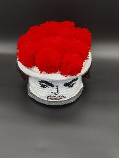 a red and white hat with a face on it