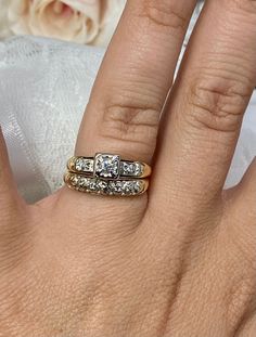 a woman's hand with two wedding rings on it and a bouquet in the background