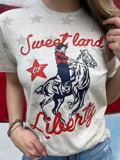 Saddle up for some patriotic fun with our Plus Sweet Land of Liberty Cowboy Graphic Tee! This 4th of July t-shirt will have you looking stylish while showing off your love for America. Yee-haw! Color: Natural Heather Fabric: 100% Cotton Brand: Ask Apparel Made: USA Includes: x1 T-Shirt Sizes: S - XL, Regular Sizing Americana Cotton T-shirt With Letter Print, Fun 4th Of July Crew Neck T-shirt, Fun Crew Neck T-shirt For 4th Of July, Fun Cotton T-shirt With American Flag Print, Fun Graphic Print Tops For Independence Day, Fun American Flag Print T-shirt For Independence Day, Fun American Flag Print Short Sleeve T-shirt, Fun American Flag Print Crew Neck T-shirt, Fun American Flag Print T-shirt Crew Neck