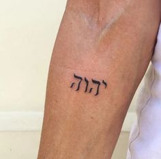 a person with a tattoo on their arm that has the word hebrew written in cursive letters