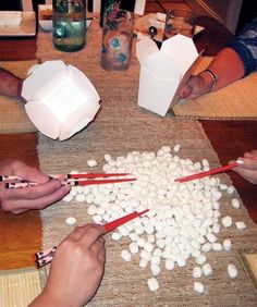 several people sitting at a table making marshmallows