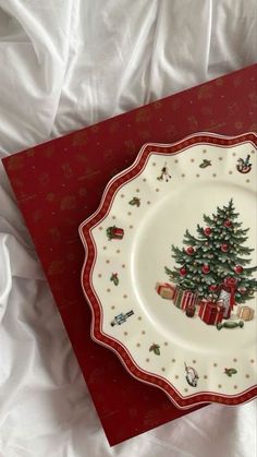 a plate with a christmas tree on it sitting on top of a red and white sheet