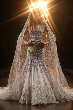 a woman in a wedding dress with a veil over her head and hands on her hips