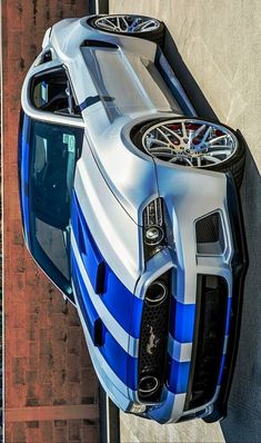 the front end of a blue and white sports car parked next to a tall building