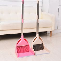 two mop and brooms on the floor in front of a couch