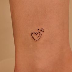 a small heart tattoo on the side of a woman's stomach, with two butterflies flying around it