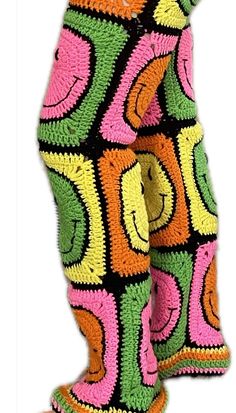 a pair of colorful socks with smiley faces on the legs and feet, all made out of multi - colored crocheted yarn