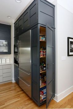 a pantry in the middle of a kitchen with stainless steel appliances and wood flooring