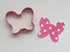 two cookie cutters with pink and white polka dots on them, one is shaped like a butterfly