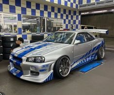 a silver car with blue stripes parked in a garage