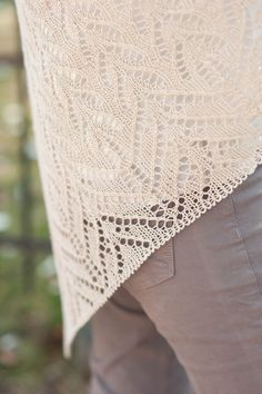 a close up of a person wearing a white lace shawl over their shoulders and pants