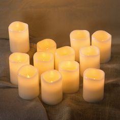 many lit candles are arranged in the shape of a heart on a brown fabric background